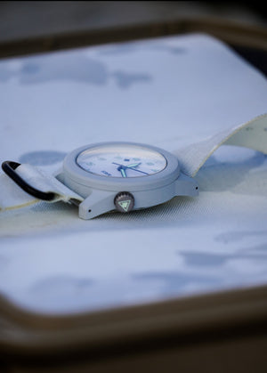 Close-up of a Cerakote Snow White Field-1 timer watch featuring a lumed ARES arrow crown on a Multicam Alpine white camouflage-patterned strap.