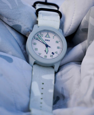 Cerakote Snow White field timer watch with a Multicam Alpine white camouflage-patterned strap.
