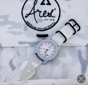 Close-up of a Cerakote Snow White Field-1 timer watch featuring a lumed ARES arrow crown on a Multicam Alpine white camouflage-patterned strap.